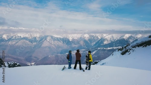 Aerial shot group of young active sports people admiring of beautiful winter landscape with high mountains covered by white snow. Shooting from helicopter wonderful north nature