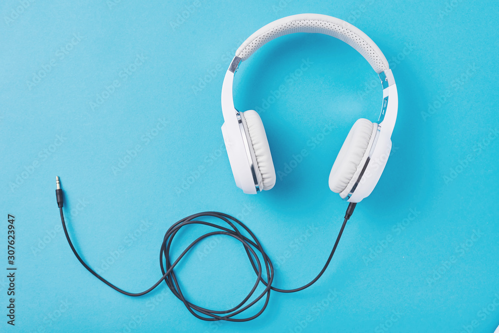 White headphones with cable on a blue background White headphones with cable on a blue background