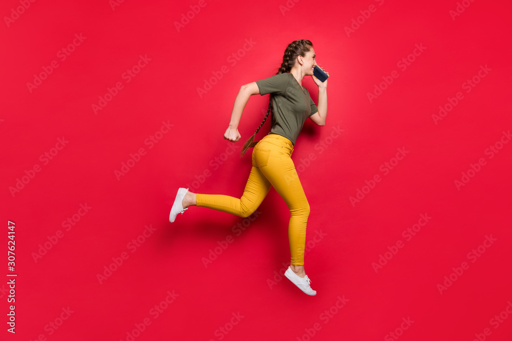 I'm on my way. Full length photo of active lady jumping high running fast meeting with friends speaking telephone wear casual pants t-shirt isolated red color background I'm on my way. Full length photo of active lady jumping high running fast meeting with friends speaking telephone wear casual pants t-shirt isolated red color background