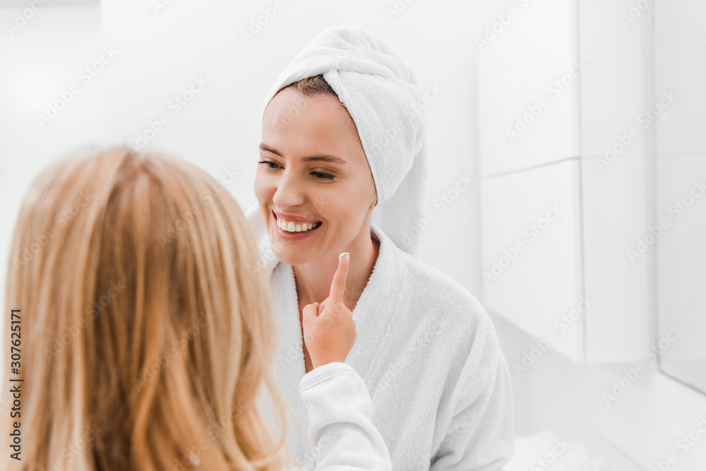back view of kid applying cosmetic cream face of happy mother back view of kid applying cosmetic cream face of happy mother