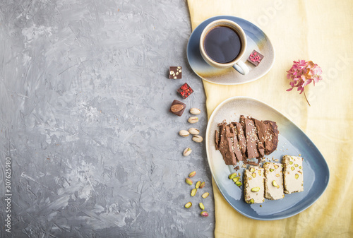 traditional arabic sweets sesame halva with chocolate and pistachio and a cup of coffee on a gray concrete background. top view, copy space. photo