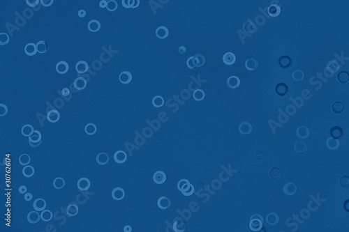 Monochrome metallic foil confetti background. Trendy blue colored circles sparse on classic blue colored paper. Simple holiday concept. Top view, flat lay. Color of the year 2020trend concept.