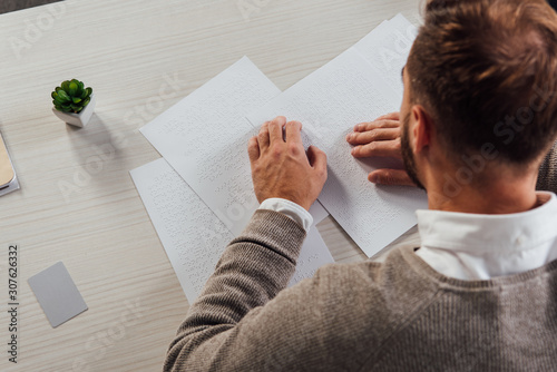 Overhead view of blind man reading braille font beside card with copy space on table