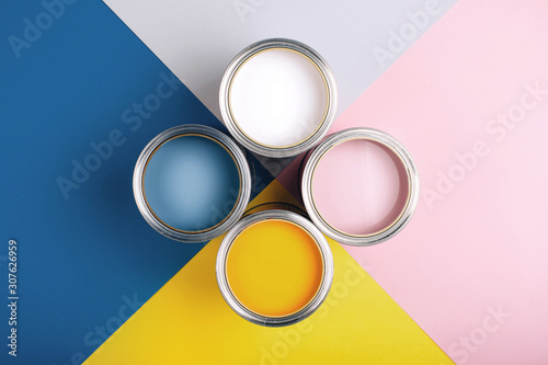 Fototapeta Naklejka Na Ścianę i Meble -  Four open cans of paint on bright symmetry background. Yellow, white, pink, blue colors of paint. Place for text. Renovation concept.