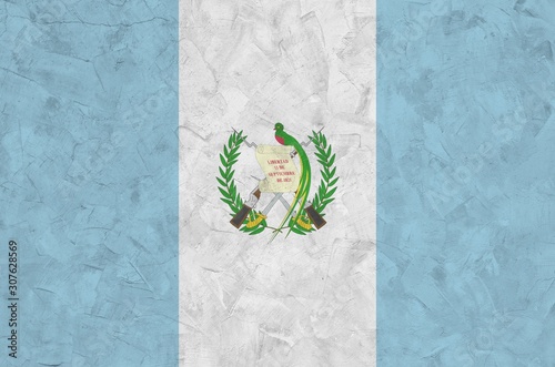 Guatemala flag depicted in bright paint colors on old relief plastering wall. Textured banner on rough background photo