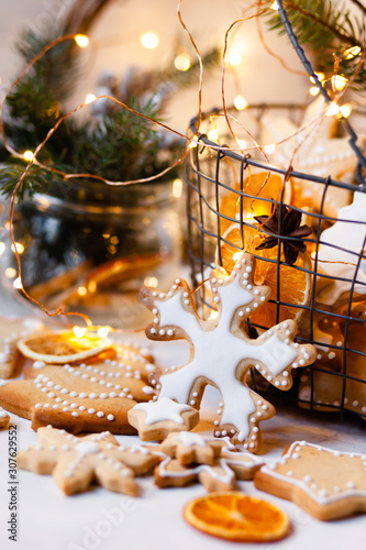 Metal basket with delicious homemade gingerbread cookies decorated with icing. Rustic decor  christmas lights on. Festive mood  holiday atmosphere. Front view  closeup  white background