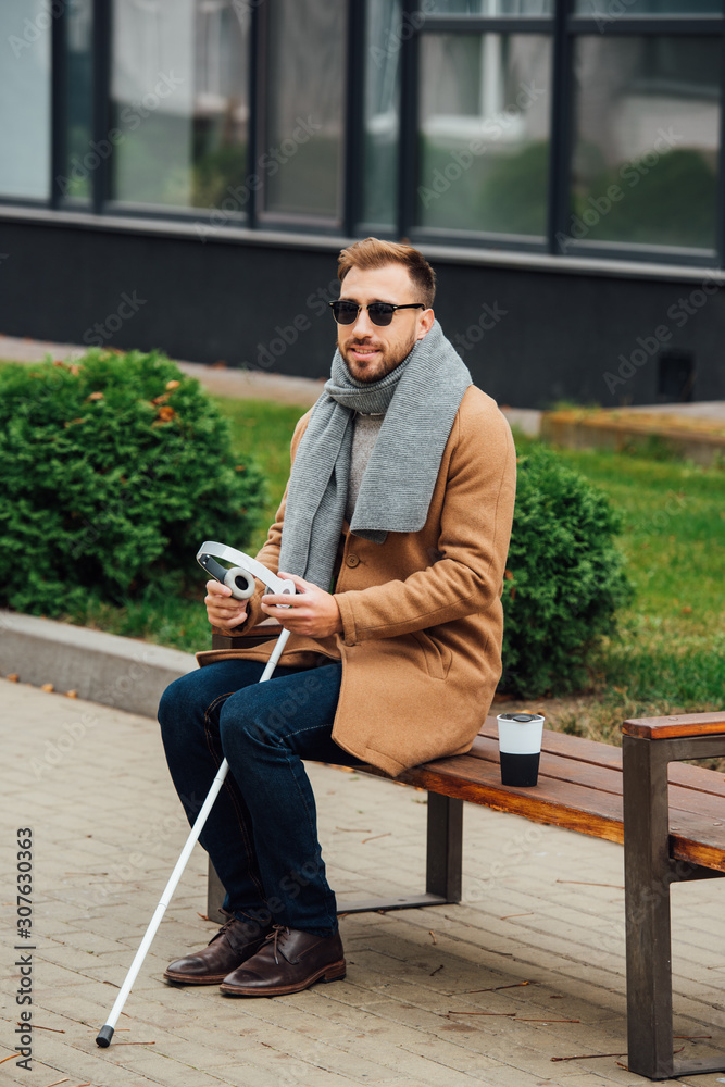 Obraz premium Blind man holding headphones while sitting on bench
