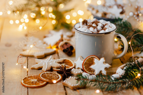 Winter hot drink: white mug with hot chocolate with marshmallow and cinnamon. Cozy home atmosphere, festive holiday mood. Rustic style, wooden background. Homemade gingerbread cookies