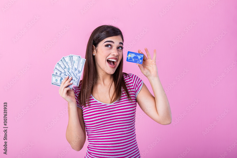Photo of caucasian brunette woman 20s smiling while holding credit card and fan of dollar cash isolated over pink background Photo of caucasian brunette woman 20s smiling while holding credit card and fan of dollar cash isolated over pink background