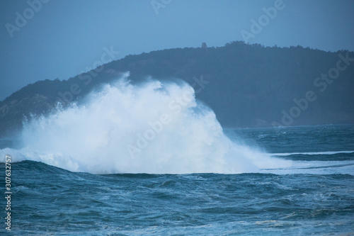 Close-up of a big wave breaking in the ocean against a rock