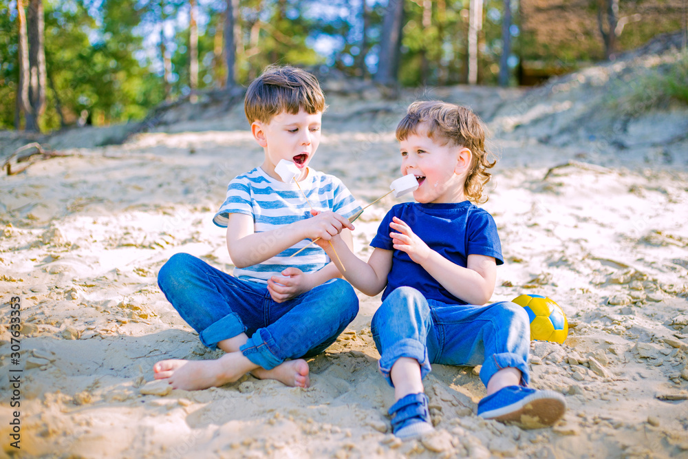 Cute kids feeding each other marshmallow on the beach Cute kids feeding each other marshmallow on the beach
