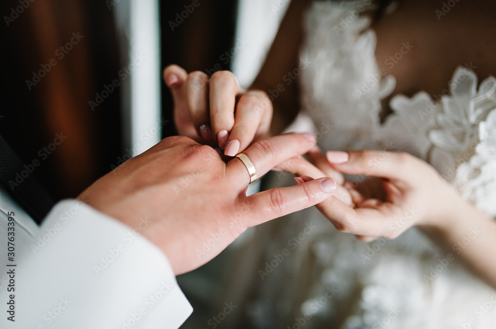 The hands of the bride wears a wedding engagement ring on the finger of the groom. Preparations. Wedding ceremony. Jewelry. close up. Newlyweds.