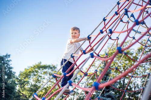 Cute kid climbing on playground in park