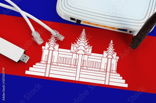 Cambodia flag depicted on table with internet rj45 cable, wireless usb wifi adapter and router. Internet connection concept photo