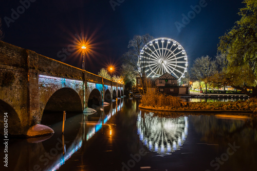 The ferris wheel at Waterside, Stratford upon Avon, illuminated against the night sky and reflected in the River Avon.