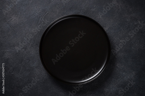 Black plate on black stone table top view.