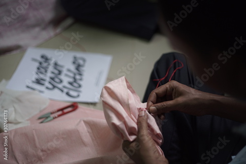 Man sewing by hand with a red thread