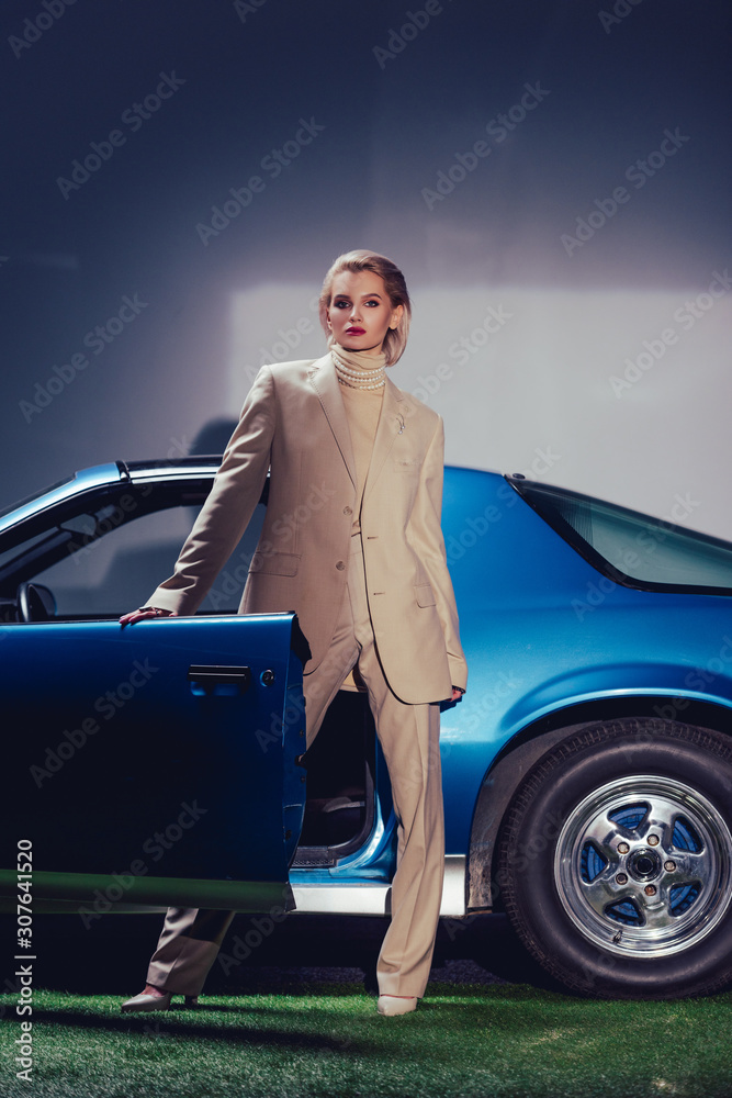 attractive and stylish woman in suit standing near retro car