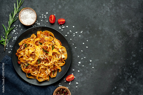 Fototapeta Naklejka Na Ścianę i Meble -  Pasta Bolognese with spices, Italian pasta dish with minced meat and tomatoes in a dark plate on a stone background with copy space for your text