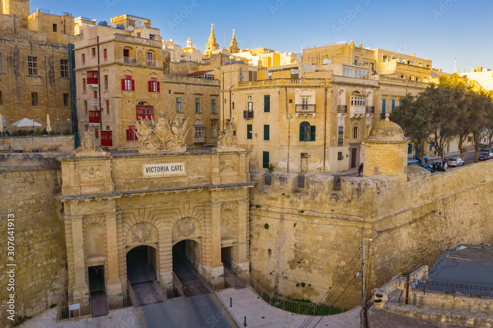 Fototapeta premium Aerial view of Victoria gate in Valletta. The traditional houses, buildings and red maltese balcony on blue sky. Malta country