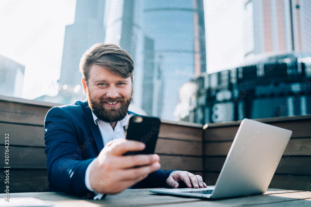 Man smiling at camera while holding mobile phone in hand Man smiling at camera while holding mobile phone in hand
