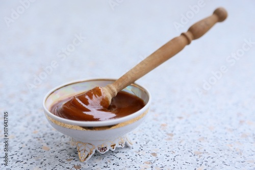 Thick honey and a spoon of wood in a glass plate -cremanque