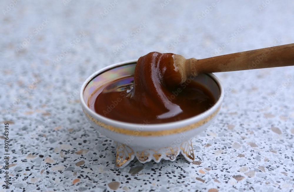 Spoon of wood for honey and honey in a socket on the table Spoon of wood for honey and honey in a socket on the table