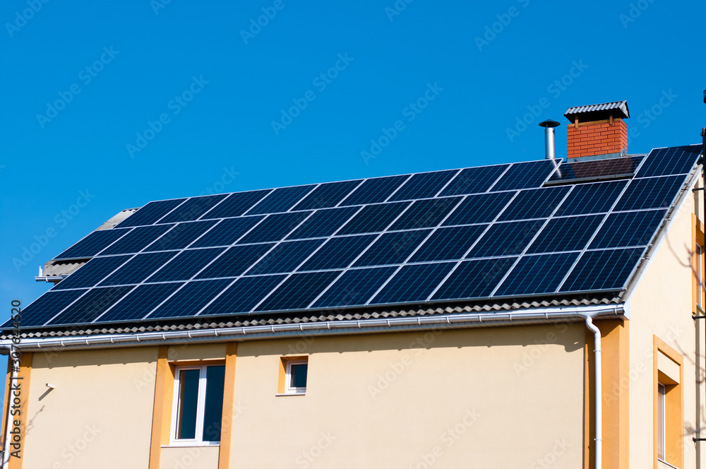 Solar panel system on house roof, sunny blue sky background.Blue solar panels. Solar panel system on house roof, sunny blue sky background.Blue solar panels.