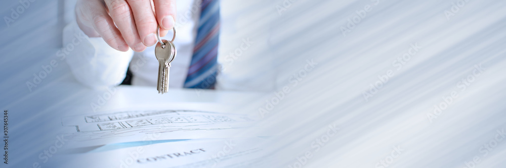 Estate agent holding house keys; panoramic banner Estate agent holding house keys; panoramic banner