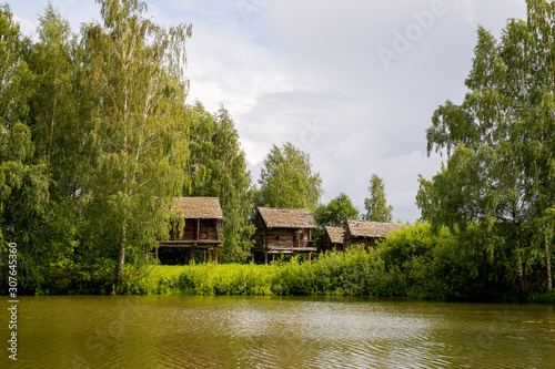 Rural landscape. Sheds for storage of agricultural goods are located on the river Bank among the birches. Kostroma, Russia.