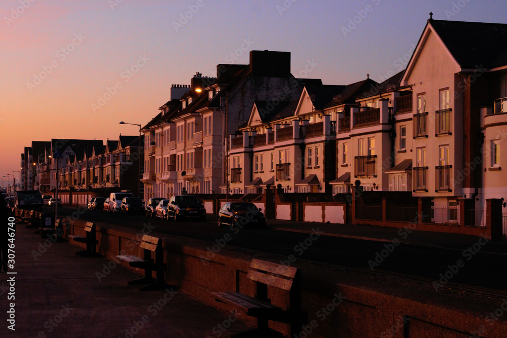 Fototapeta premium Seafront street with houses at sunset in Seaford, United Kingdom.
