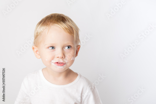 Portrait of fair-haired boy with chocolate on his face isolated on white.