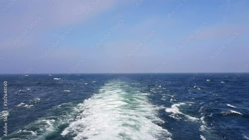 Powerful waves following the ship. Waves behind the stern of the ship. Track from the engines of the ship. Cruise liner sails on the blue ocean. The waves from the ship go to the horizon. Powerful waves following the ship. Waves behind the stern of the ship. Track from the engines of the ship. Cruise liner sails on the blue ocean. The waves from the ship go to the horizon.