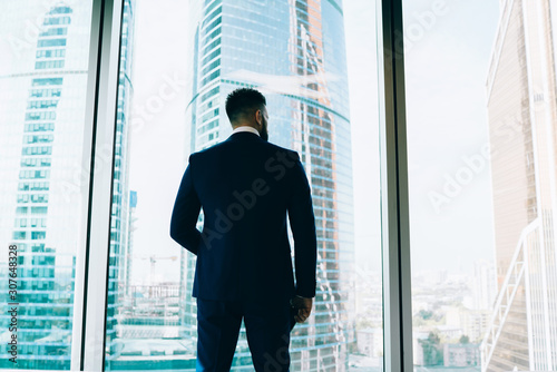 Confident employee looking out window on cityscape