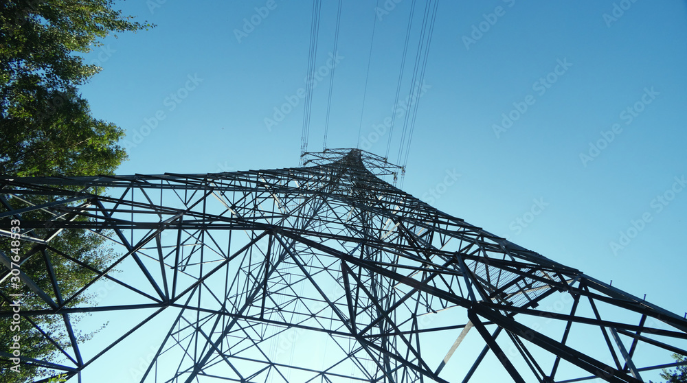 abstract shapes of an electricity pylon from underneath against a bright blue vivid sky backdrop. electricity  transportation across metal wires.