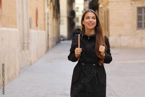 Young curious woman travelling and visiting Europe in winter time. Backpacker girl walking in Valencia admiring spanish architecture.