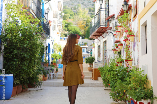 Visiting Alicante in Spain. Young tourist woman visits the neighborhood Santa Cruz of Alicante in Spain. Tourist girl exploring european city with typical Mediterranean architecture and decoration.