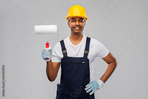 repair, construction and building - happy smiling indian builder or painter in helmet with paint roller over grey background photo