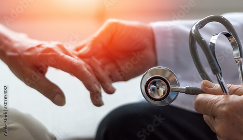 Geriatric doctor or geriatrician concept. Doctor physician hand on happy elderly senior patient to comfort in hospital examination room or hospice nursing home or wellbeing county. photo