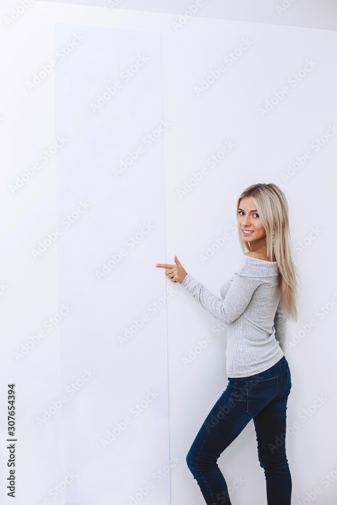 Beautiful girl in a sweater and jeans on a white background points finger Beautiful girl in a sweater and jeans on a white background points finger