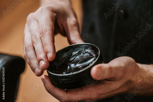 cropped view of man holding jar with black hair pomade