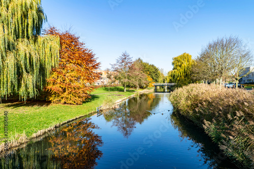 Autumn park with a pond, in which is reflected the blue sky. Bright autumn landscape with yellow leaves on a background of blue sky. Autumn sunny day in the Dutch city of Almere. photo