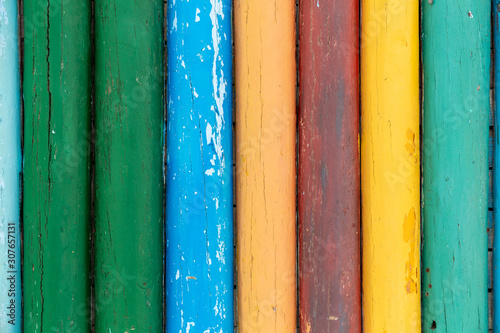 Closeup top view of rounded planks of wooden house or fence painted with bright colorful different colors. Horizontal color photography.