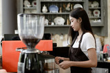 Happily of young girl barista making coffee in shop cafe and preparing brew espresso coffee near counter. Coffee making cafe barista concept, Small business owner and work concept.
