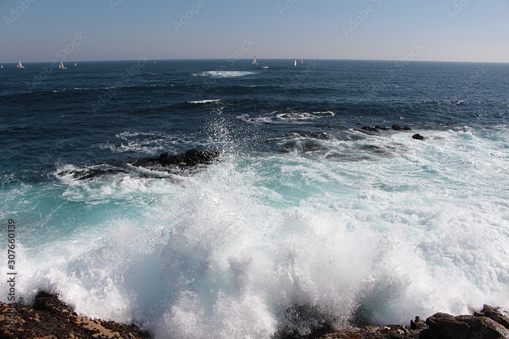 Movement on the shore. A view of sea waves bursting on the rocks and forming foam in Algarrobo beach in Chile