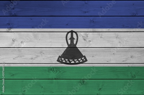 Lesotho flag depicted in bright paint colors on old wooden wall. Textured banner on rough background photo