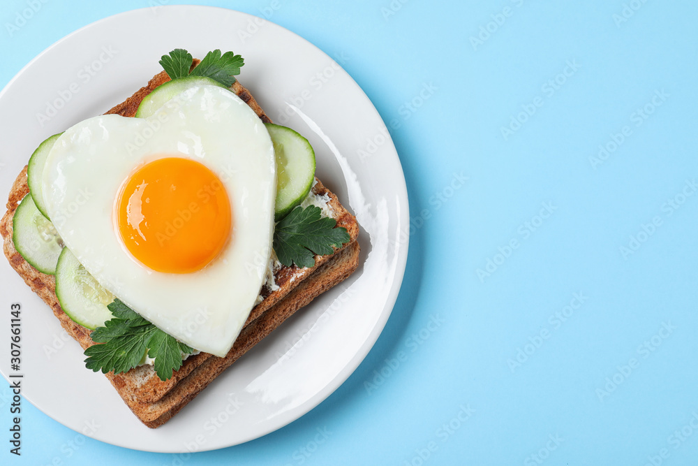 Plate of tasty sandwich with heart shaped fried egg on light blue background, top view. Space for text Plate of tasty sandwich with heart shaped fried egg on light blue background, top view. Space for text