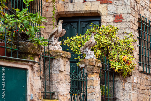 Flowers and eagle sculptures on entrance gate of old buildings on Montmartre, Paris. Autumn in France, old town.