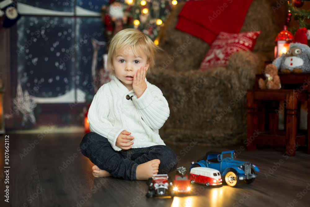 Cute toddler boy, sitting around many car toys on the floor, playing Cute toddler boy, sitting around many car toys on the floor, playing