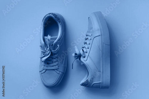 Woman fashion mint shoes on classic blue background with copy space. Top view. Trendy classic blue background. Fitness, sport concept. Nude female sneakers